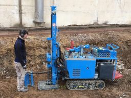 Mann bedient eine blaue Maschine im hohen Gras. Kleinrammbohrung (KRB) zur Bodenuntersuchung.