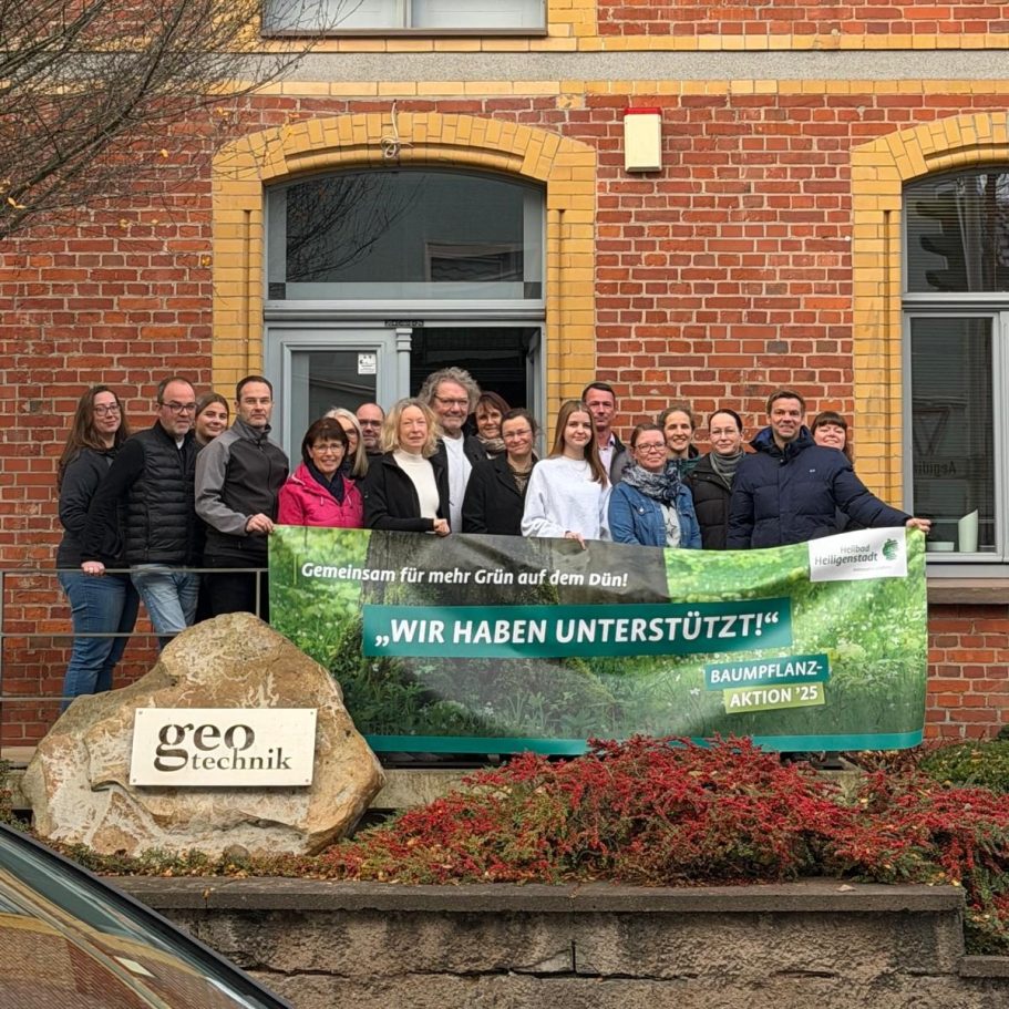 Gruppenfoto von Mitarbeitern vor einem dem Gebäude mit einem Banner zur Unterstützung von Projekten.