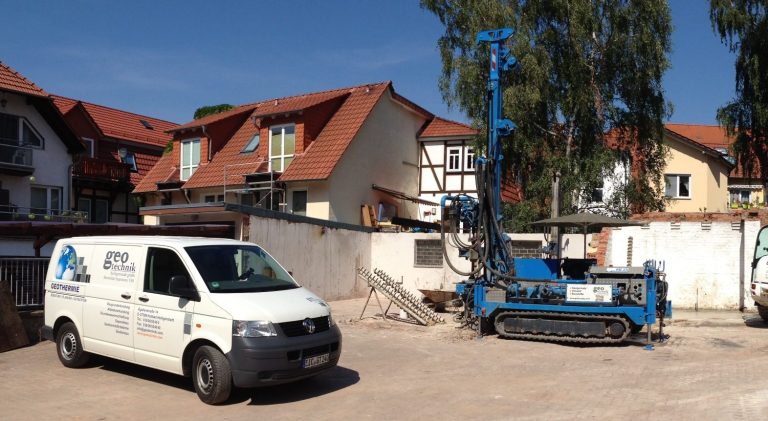 Innenhof mit Transporter und einem blauen Bohrgerät vor Mehrfamilienhäusern.