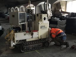 Ein Arbeiter überprüft eine kleine, geländegängige Maschine in einer Lagerhalle.