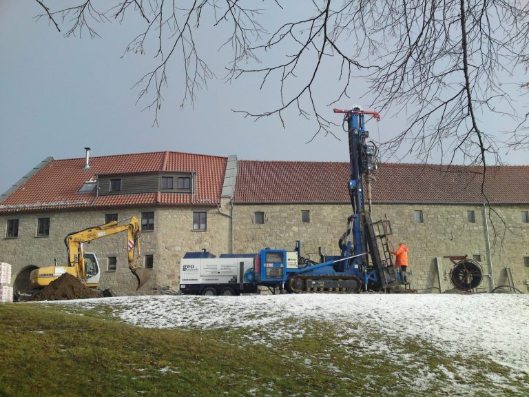 Baustelle mit Baugerät und einem Bohrgerät vor einem Sandsteingebäude in Scharfenstein im Winter.