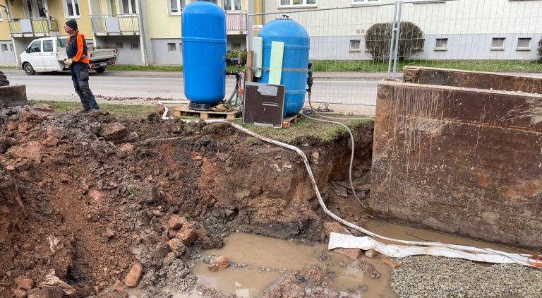 Eine Baugrube mit zwei blauen Tanks und einem Schlauch in einem Vernässungsbereich.